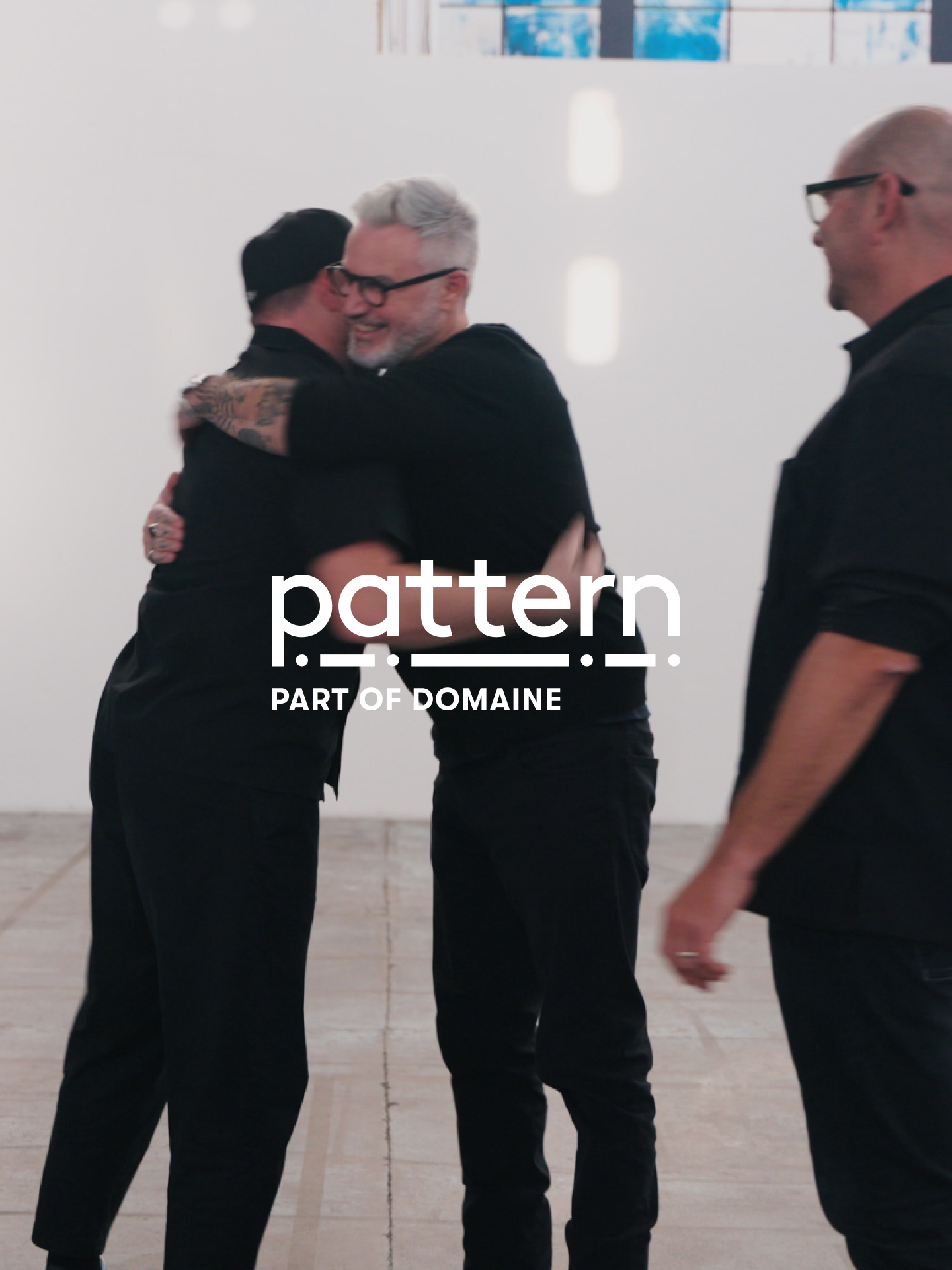 Marko, Mike, and Isaac hugging, with the Pattern Part of Domaine logo overlaid