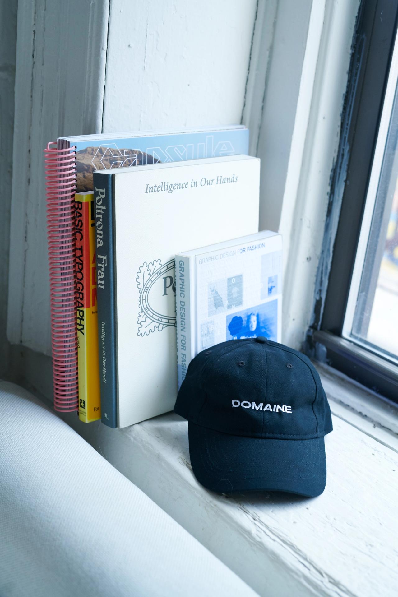Domaine hat sitting against books