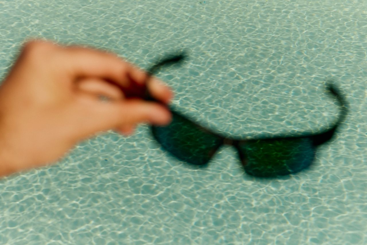 person holding sunglasses infront of a pool