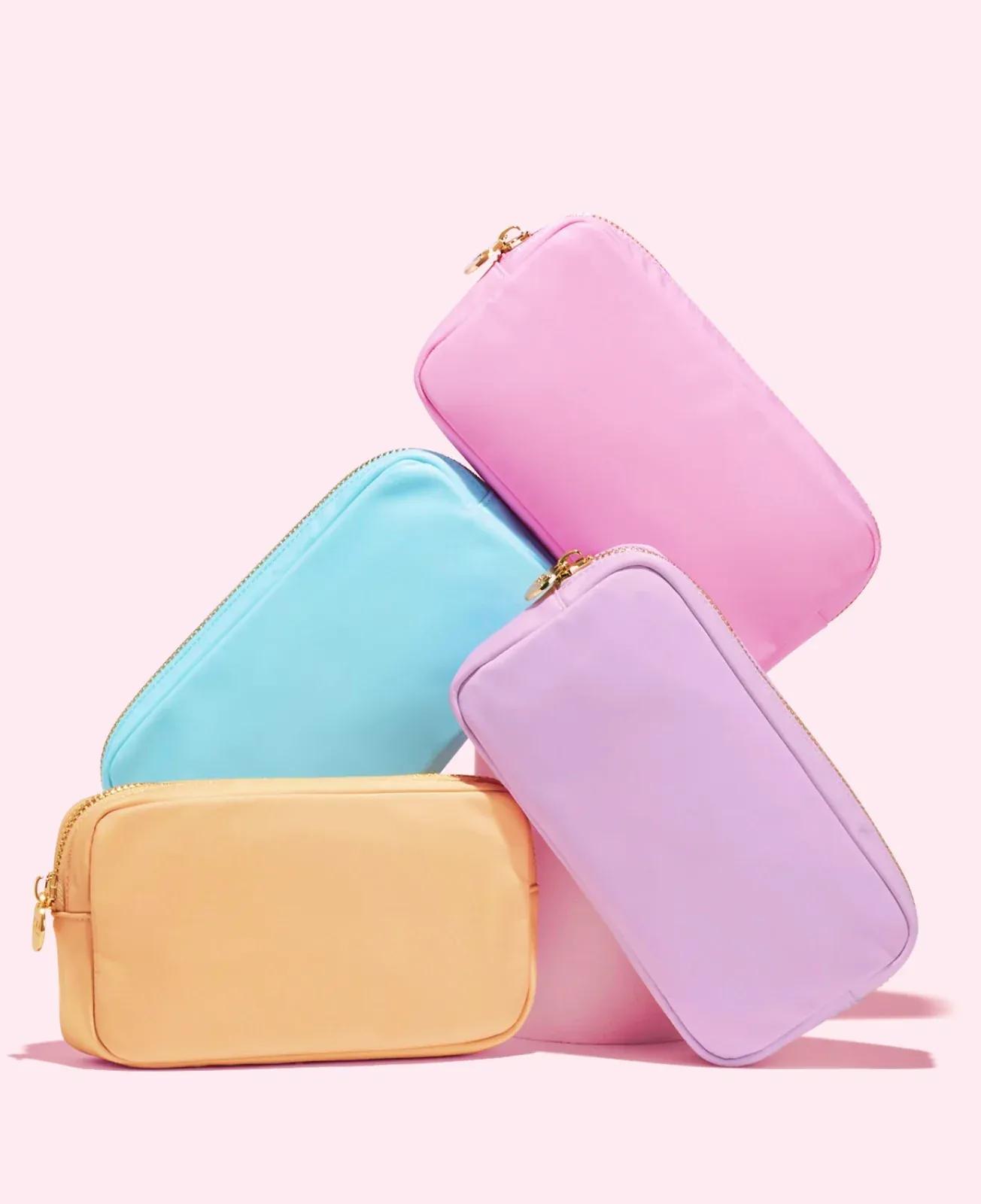 A variety of colors of Stoney Clover Lane pouches piled up on a light background