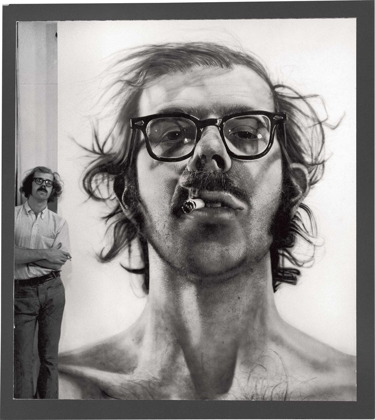 Chuck Close standing next to his Big Self-Portrait (1967–68), acrylic on gessoed canvas