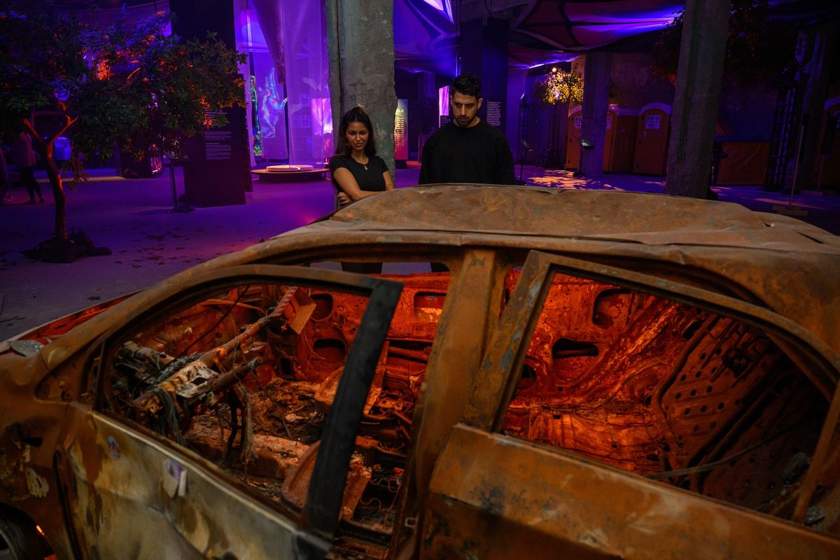 Nova survivor Natalie Sanandaji, and Reef Peretz, chairman of the Nova Foundation, look at destroyed cars taken from the Nova festival at the Nova Music Festival exhibition, October 7th 06:29 AM, The Moment Music Stood Still, in New York City Photo by Alexi Rosenfeld/Getty Images for The Nova Music Festival Exhibition
