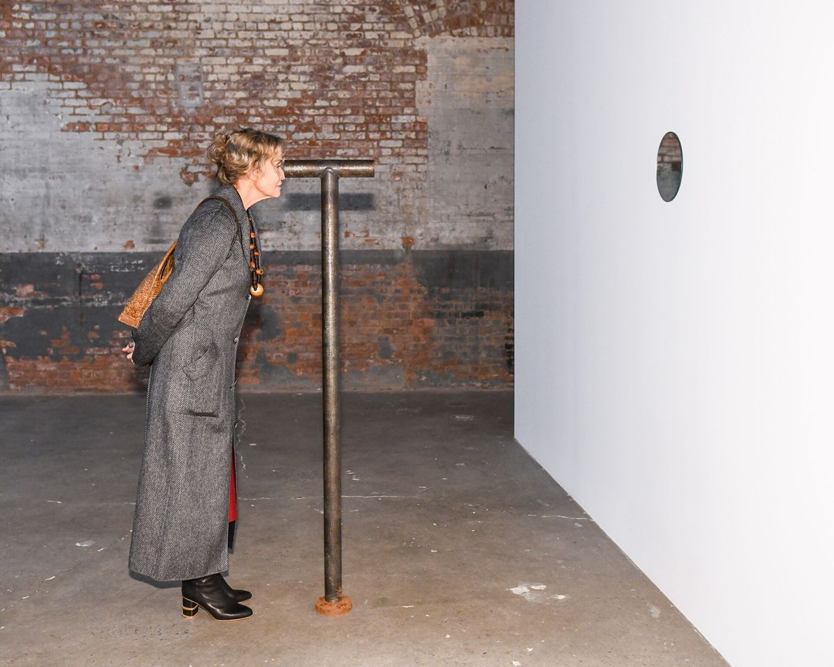 The actress Lauren Hutton peers through one of Nancy Holt's "telescopes" at Dia:Chelsea Photo: BFA