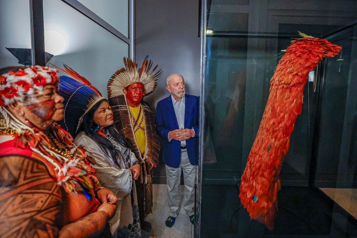 Brazilian president Luiz Inácio Lula da Silva and members of the Tupinambá Indigenous community look at the sacred cloak recently returned to Brazil, at the National Museum's Library Photo by Ricardo Stuckert, courtesy Presidency of Brazil