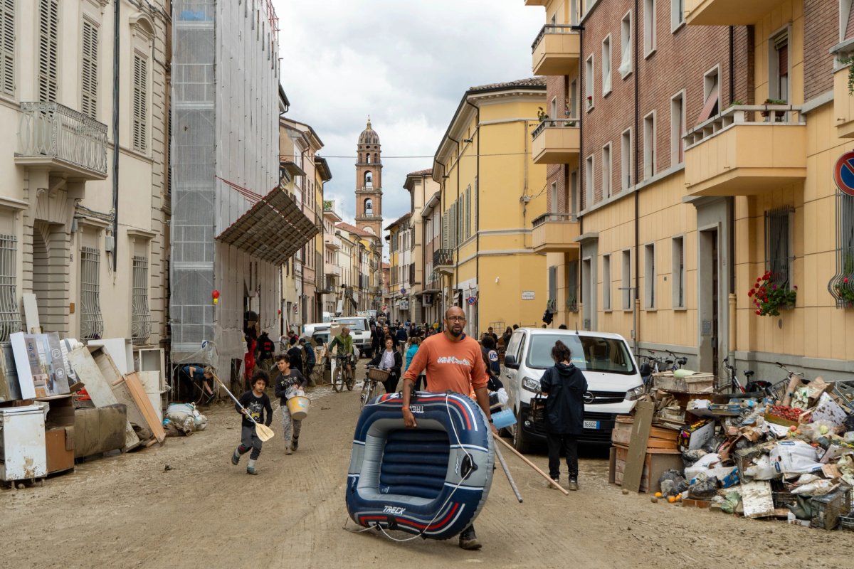 A man carries an inflatable dingy past flood-damaged debris after flooding in Faenza in the Emilia-Romagna region of northern Italy Photo: © Francesca Volpi/Bloomberg via Getty Images