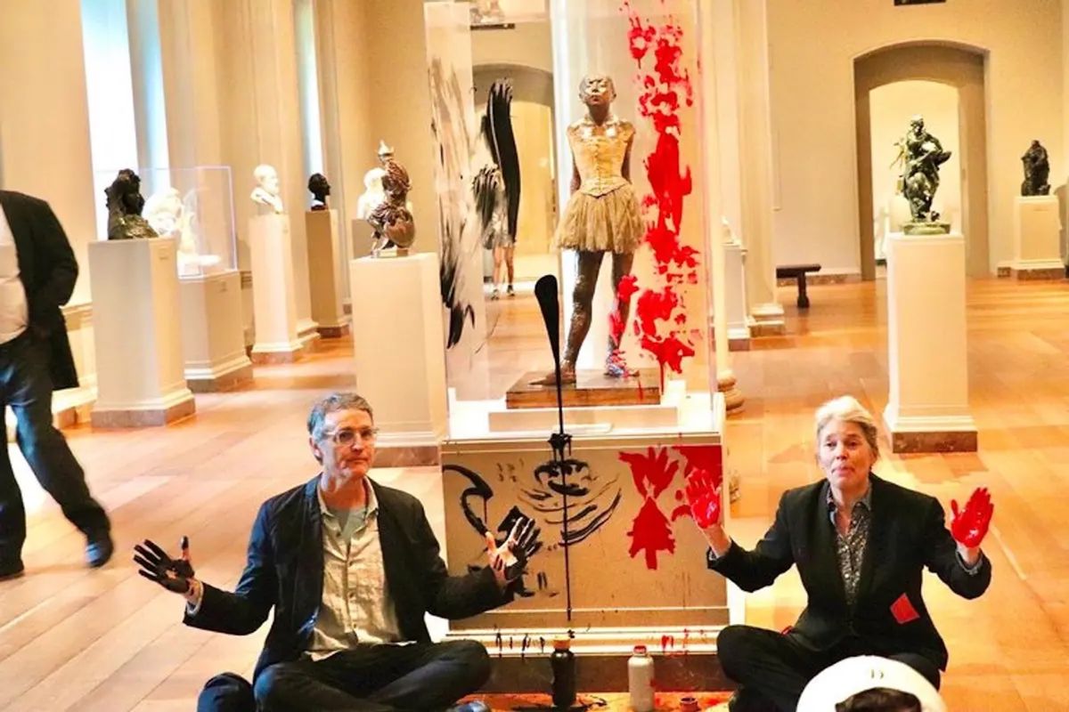 Timothy Martin (right) and Joanna Smith (left) sitting in front of La petite danseuse de quatorze ans (1880) by Edgar Degas during a climate protest at the National Gallery of Art in Washington, DC, on 27 April Courtesy of Declare Emergency