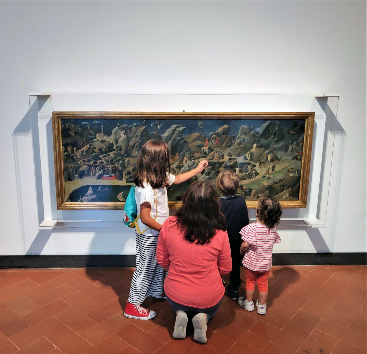 Photo of a woman and three small children looking at a painting