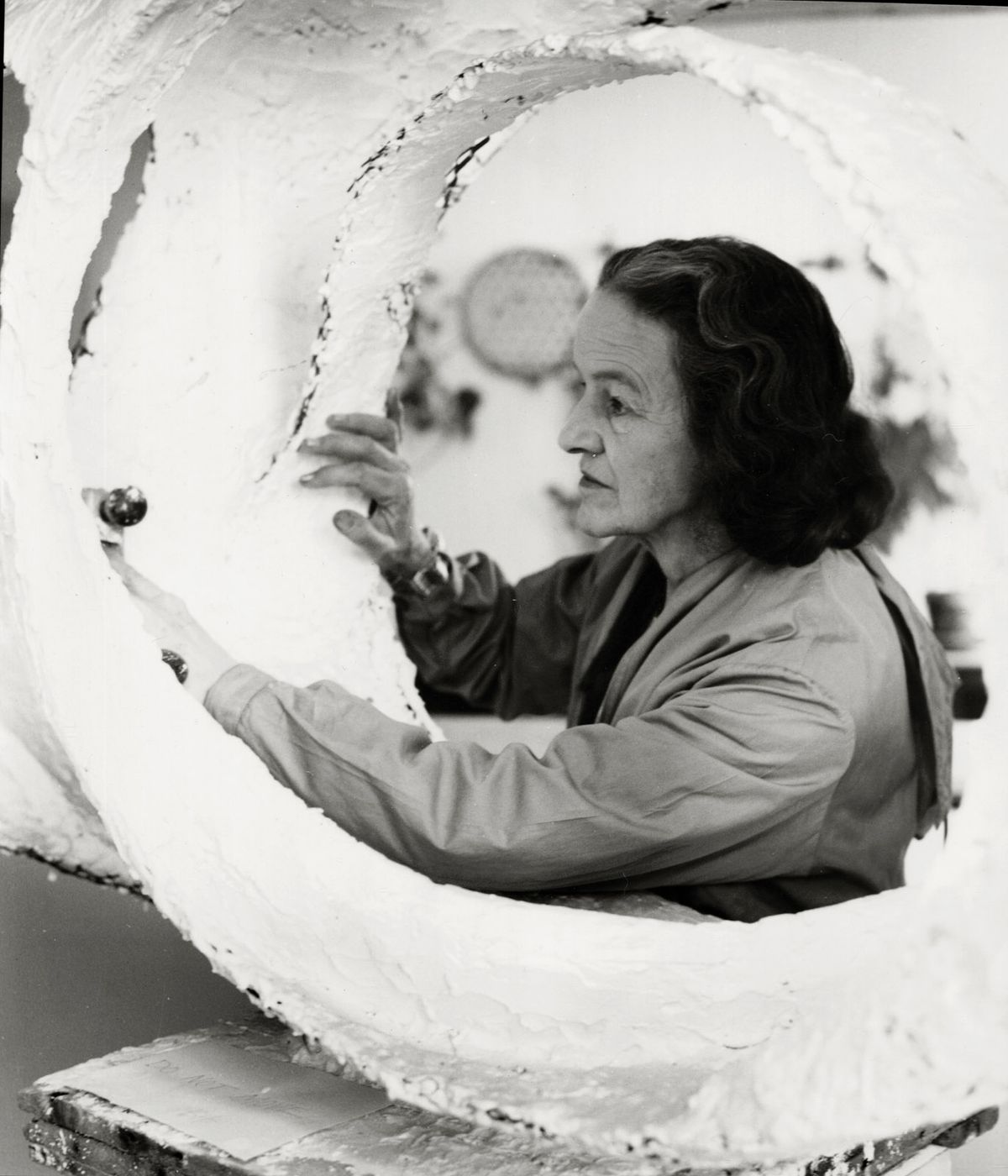 Barbara Hepworth at work in 1963 on the plaster for her sculpture Oval Form (Trezion) Photo: Val Wilmer; © Bowness, Hepworth Estate