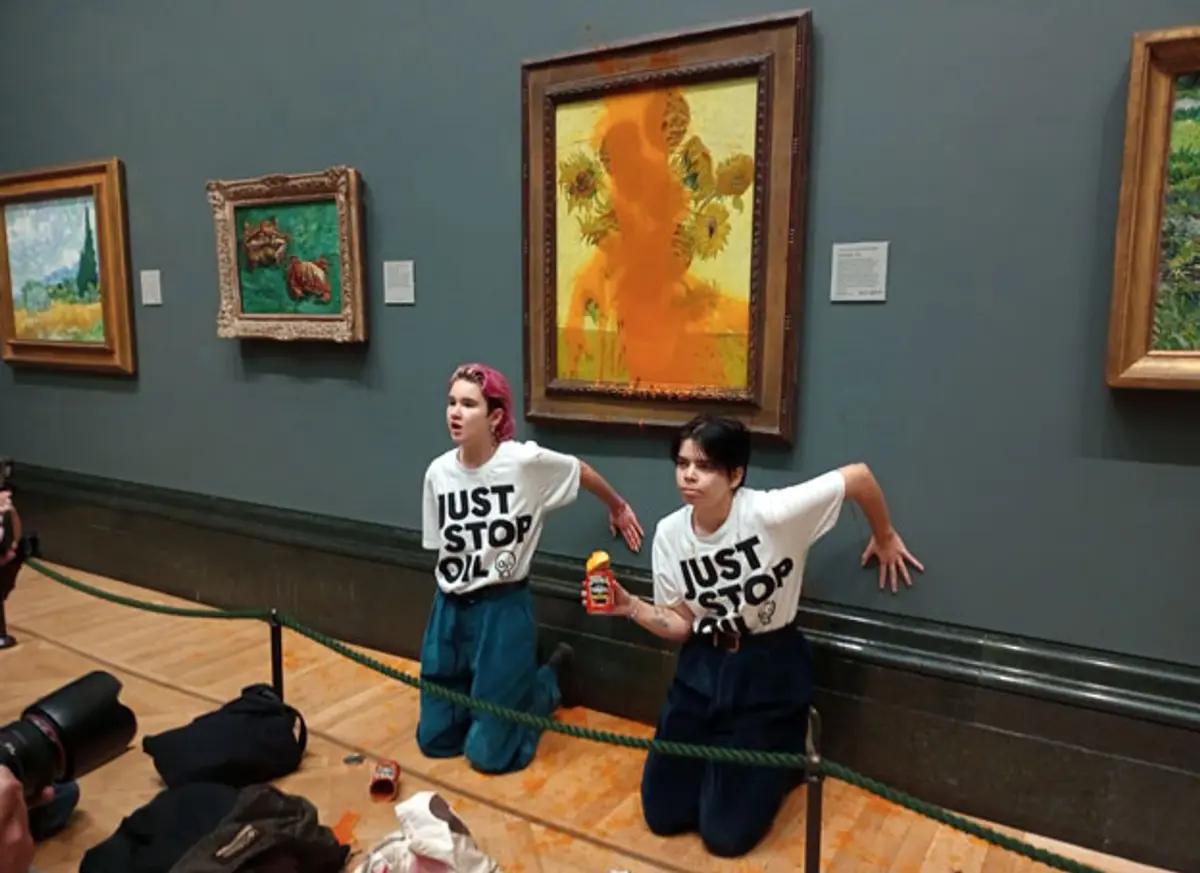 Phoebe Plummer and Anna Holland glue their hands to the wall after throwing tomato soup over Van Gogh's Sunflowers (1888)

Photo: Just Stop Oil