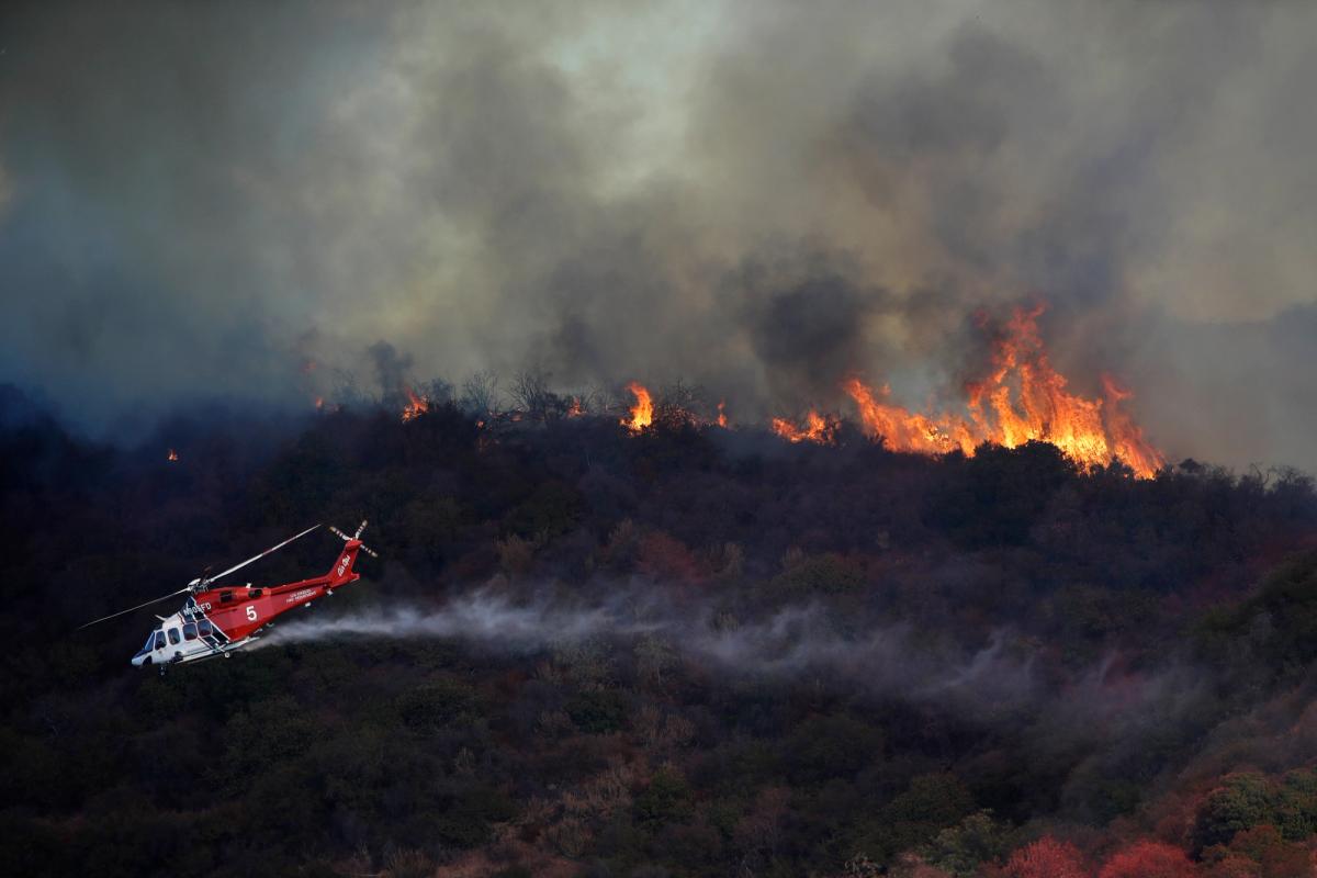 A helicopter drops water on a wildfire in Mandeville Canyon near the Getty Center in Los Angeles on Monday AP Photo/Marcio Jose Sanchez