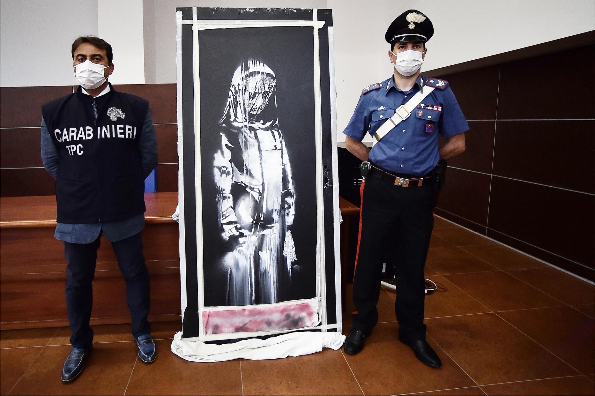 The Italian Carabinieri pose near a piece of art attributed to Banksy, that was stolen at the Bataclan in Paris in 2019, and found in Italy. Photo:  Filippo Monteforte / AFP via Getty Images