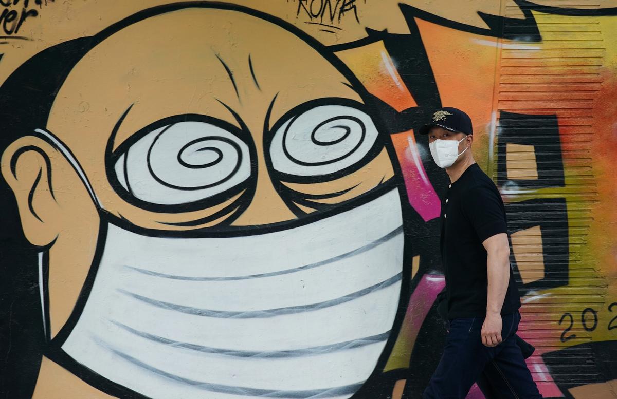 A pedestrian wears a protective mask while walking past a graffiti artwork showing a man wearing a protective mask in Shanghai, China.
Photo: Yves Dean/Getty Images