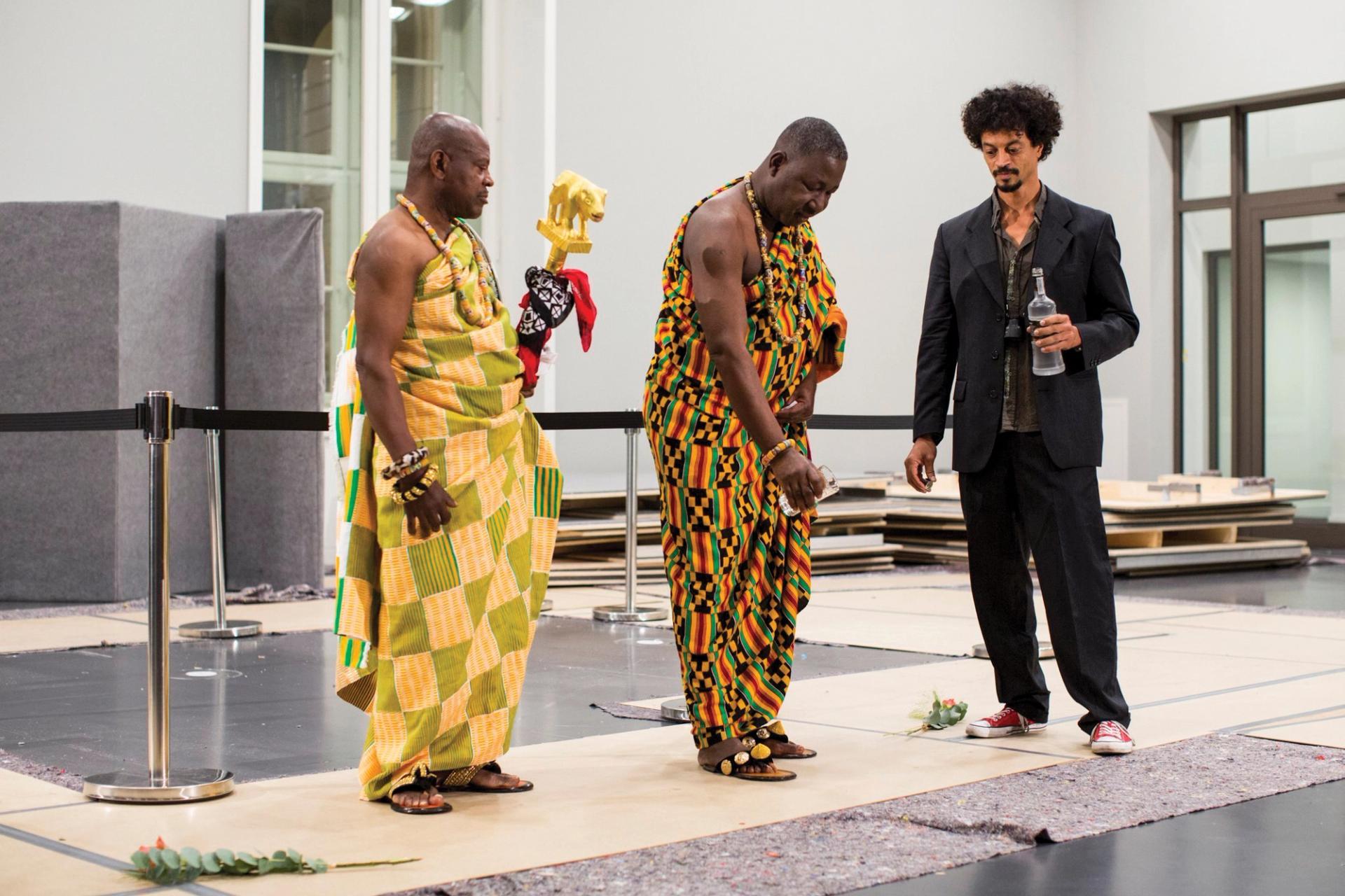 在去年洪堡论坛的表演作品《对不起，没有什么》中，德国加纳艺术家Philip Kojo Metz(右)在一个仪式上为博物馆的一个无形雕塑揭幕，与西非阿肯人©Louisa Marie Summer
