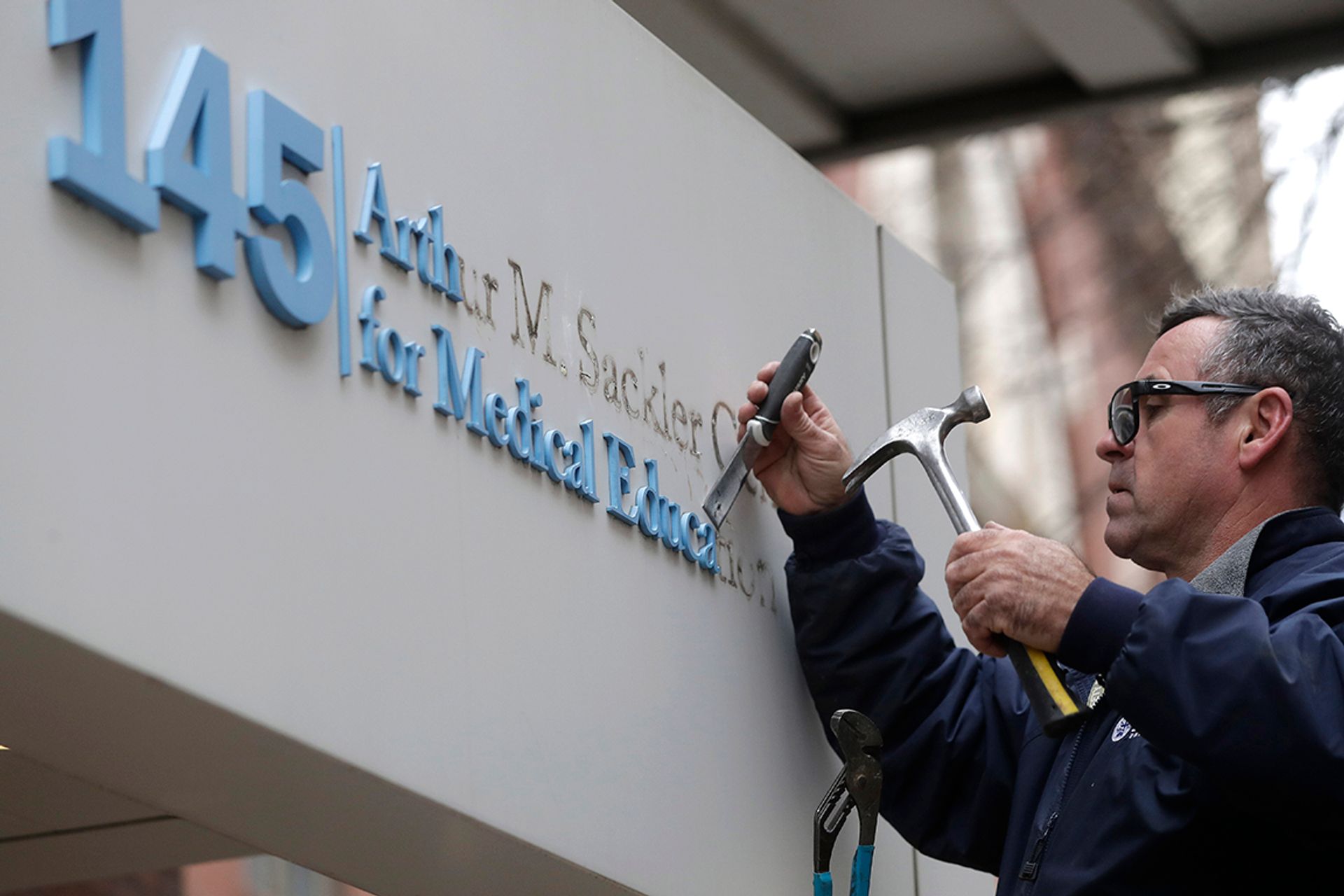 A worker removing the Sackler name today from the Arthur M. Sackler Center for Medical Education at Tufts University. The center will now be known simply as the Tufts Center for Medical Education. Steven Senne/Associated Press