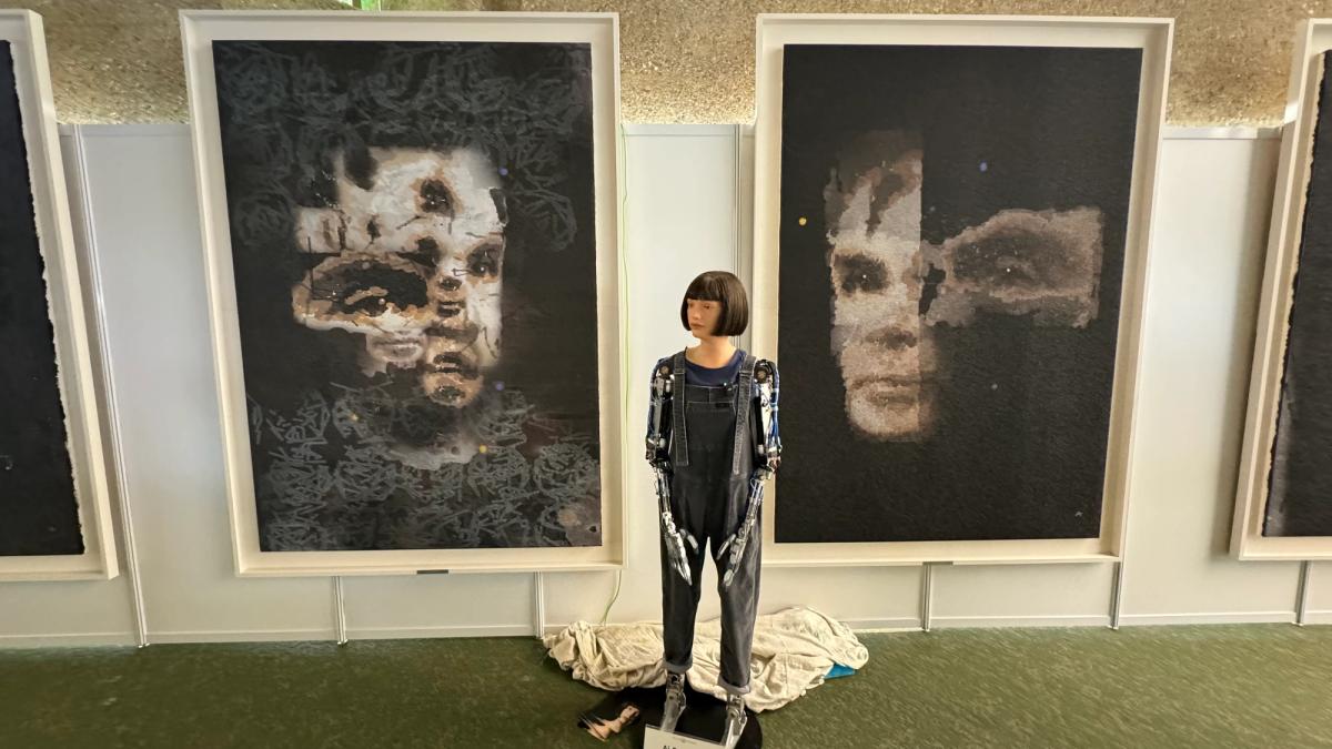 Ai-Da with her paintings at a United Nations event in Geneva. Courtesy Ai-Da Robot Studios