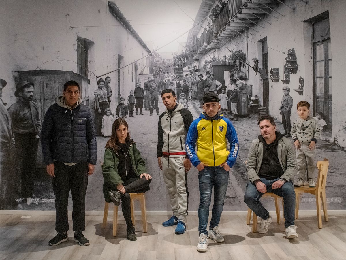 Group of visitors from La Boca neighbourhood posing in front of the mural of H.G. Olds's photograph 437. Un Conventillo. Buenos Aires, S. A. Photo by Alfredo Srur, courtesy CIFHA Foundation