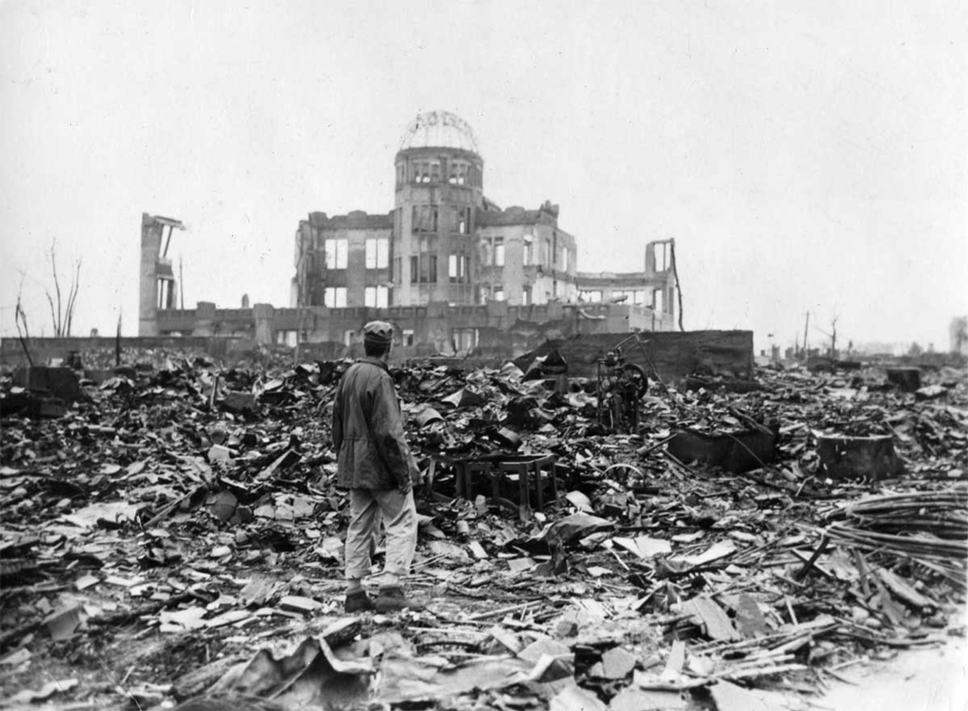 An Allied correspondent stands in rubble on 7 September 1945, looking at the ruins of the Hiroshima Prefectural Industrial Promotion Hall following the nuclear attack on the city Credit: US National Archives