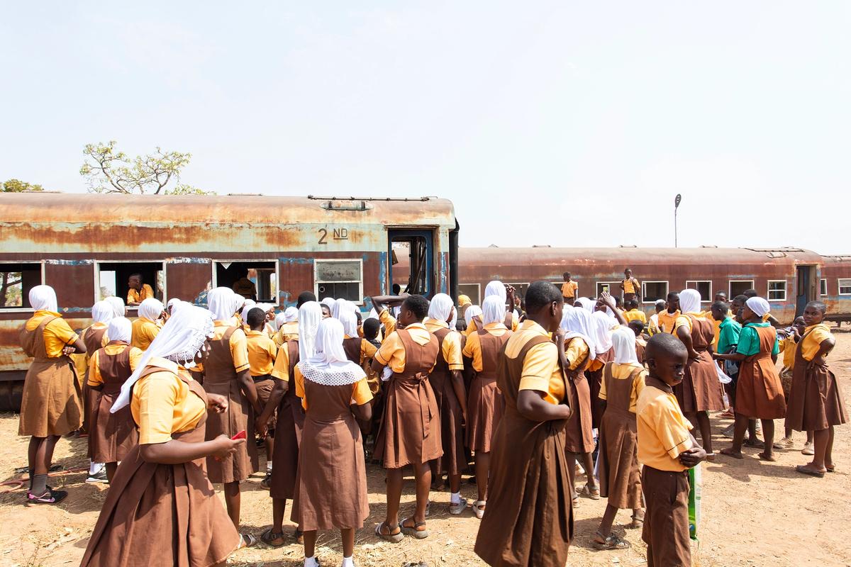 Students gather around Ibrahim Mahama's new train project at his studio in Tamale, Ghana Courtesy of Ibrahim Mahama, SCCA Tamale and Redclay