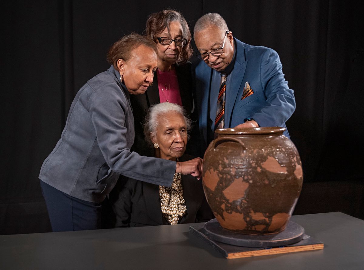 Pauline Baker, Daisy Whitner, John Williams and Priscilla Williams Carolina, descendants of the artist David Drake, at the Museum of Fine Arts, Boston, with one of the artist’s works, Jar (1857) Artwork: Ethically borrowed from the Dave the Potter Legacy Trust LLC, established for the benefit of the artist's descendants. Photo: © Museum of Fine Arts, Boston