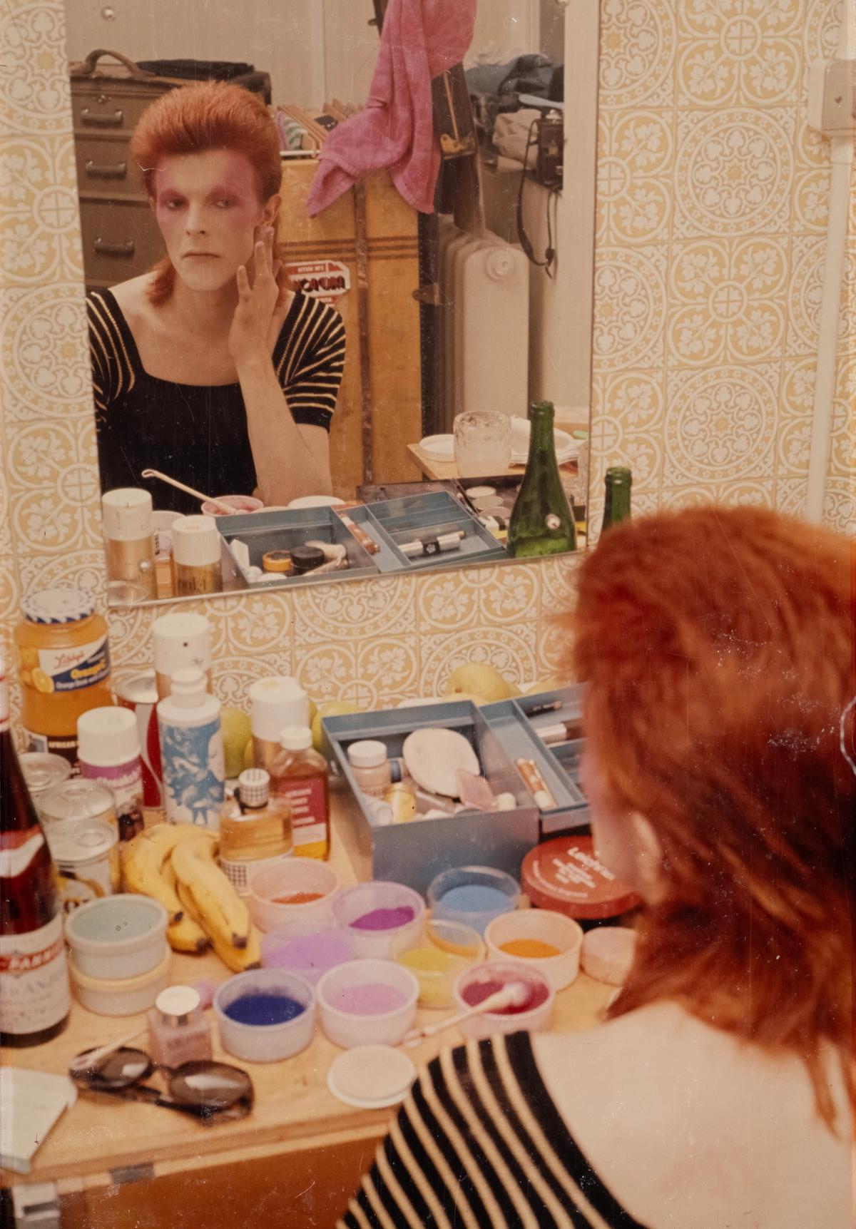 A 1973 photograph showing Bowie applying make-up as his alter ego Ziggy Stardust © Mick Rock