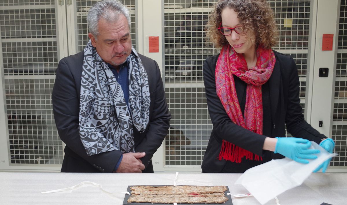 Stéphanie Leclerc-Caffarel, head of Oceanic Collections at the Musée du Quai Branly–Jacques Chirac, presents the fragment of maro 'ura to Heremoana Maamaatuiahutapu, the culture minister of French Polynesia © Gaëtan Deso