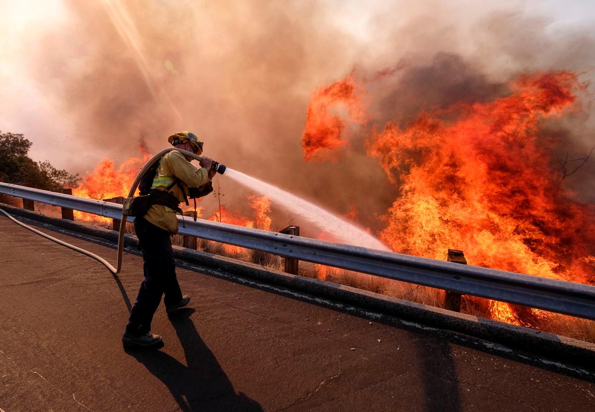 A firefighter battles a fire along the Ronald Reagan Freeway, aka state Highway 118, in Simi Valley, California, Monday, 12 November 2018 AP Photo/Ringo H.W. Chiu