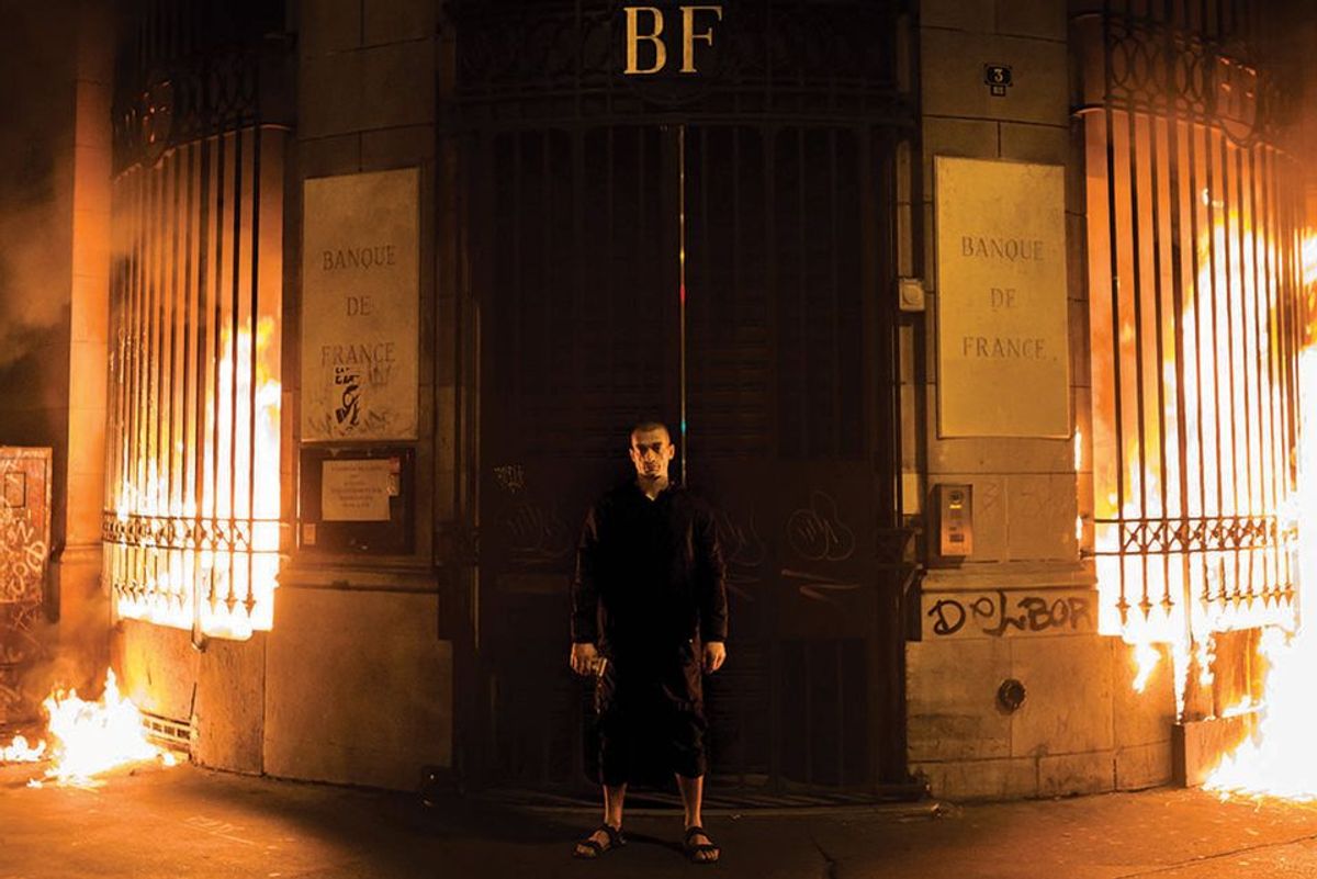 Pyotr Pavlensky poses in front of a Bank of France building after setting fire to the window gates as part of a performance in Paris ©  AP Photo/Capucine Henry