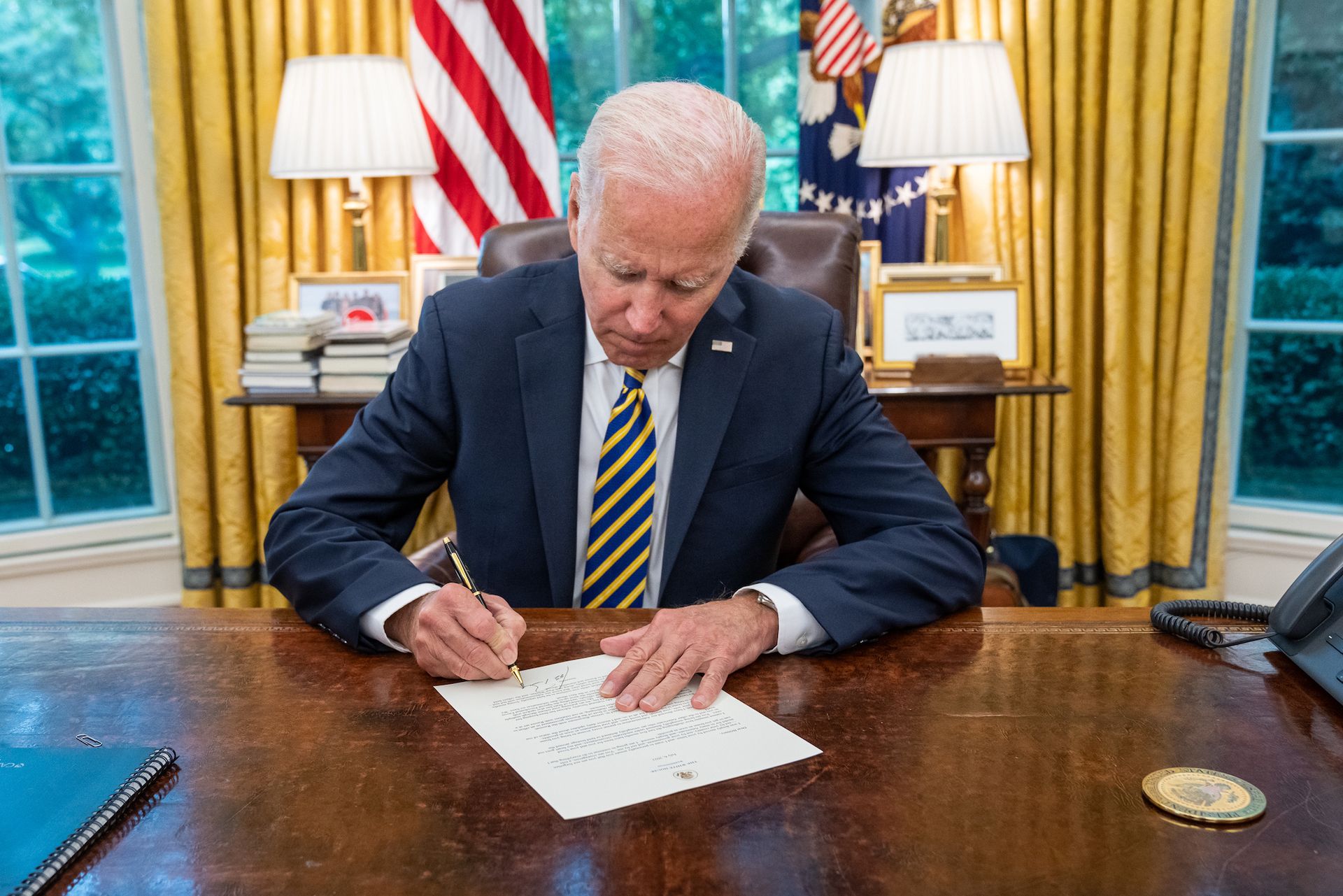 US President Joseph Biden signs a document in the Oval Office Official White House Photo by Carlos Fyfe, via Flickr