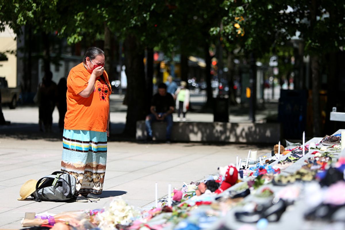 A woman mourns over a memorial by the Haida artist Tamara Bell involving 215 pairs of children's shoes on the steps of the Vancouver Art Gallery Photo by Mert Alper Dervis/Anadolu Agency via Getty Images