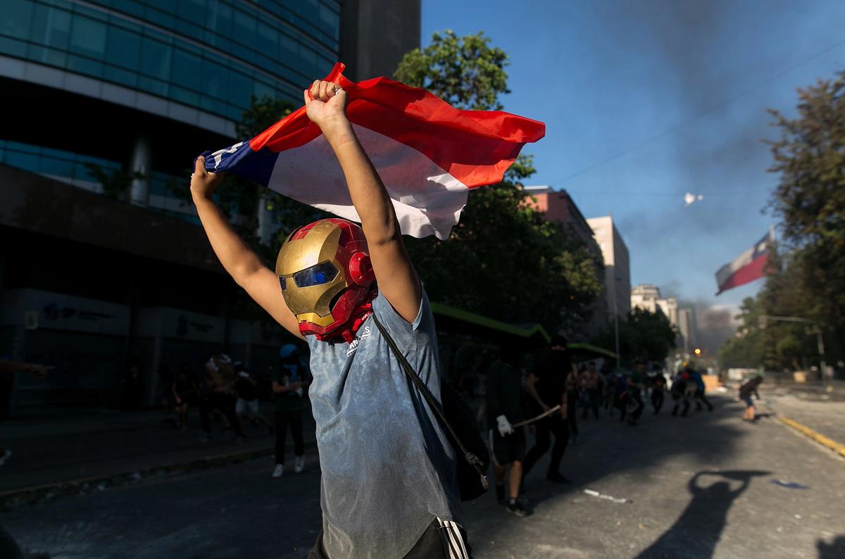 A protestor runs from pellet bullets shot by police during a protest against the economic model of President Piñera in Santiago on 28 October. Joseé Miguel Rojas/ SIPA/ Shutterstock