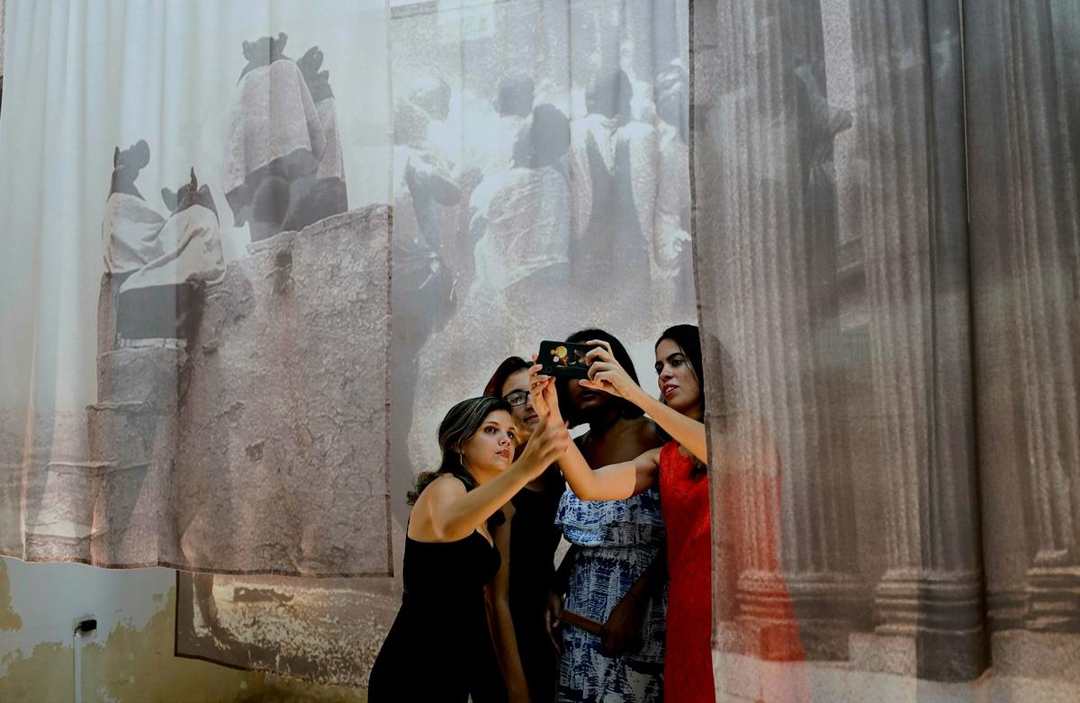 Young Cubans take a picture with a work of art by Carrie Mae Weems during the opening of the Havana Biennial © AP Photo/Ramon Espinosa