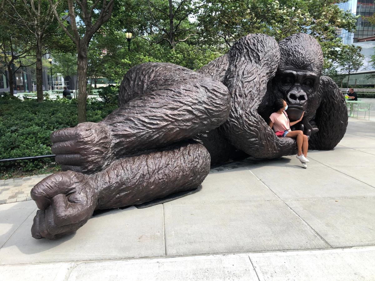 A woman poses for a photo in the hand of King Nyani, a four-and-a-half ton bronze sculpture of a silverback mountain gorilla that has been placed in Bella Abzug Park in Hudson Yards AP Photo/Ted Shaffrey