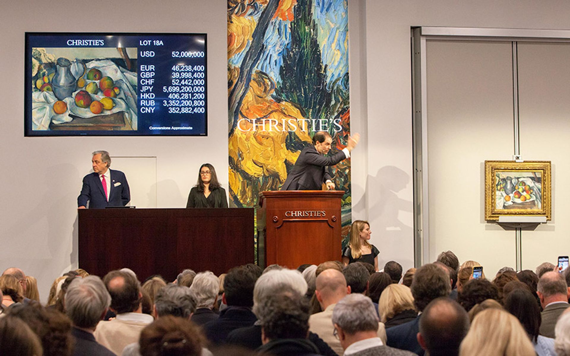 Auctioneer Adrien Meyer takes bids on the top lot of the evening, Cézanne's record-setting Boulloire et fruits Christie's