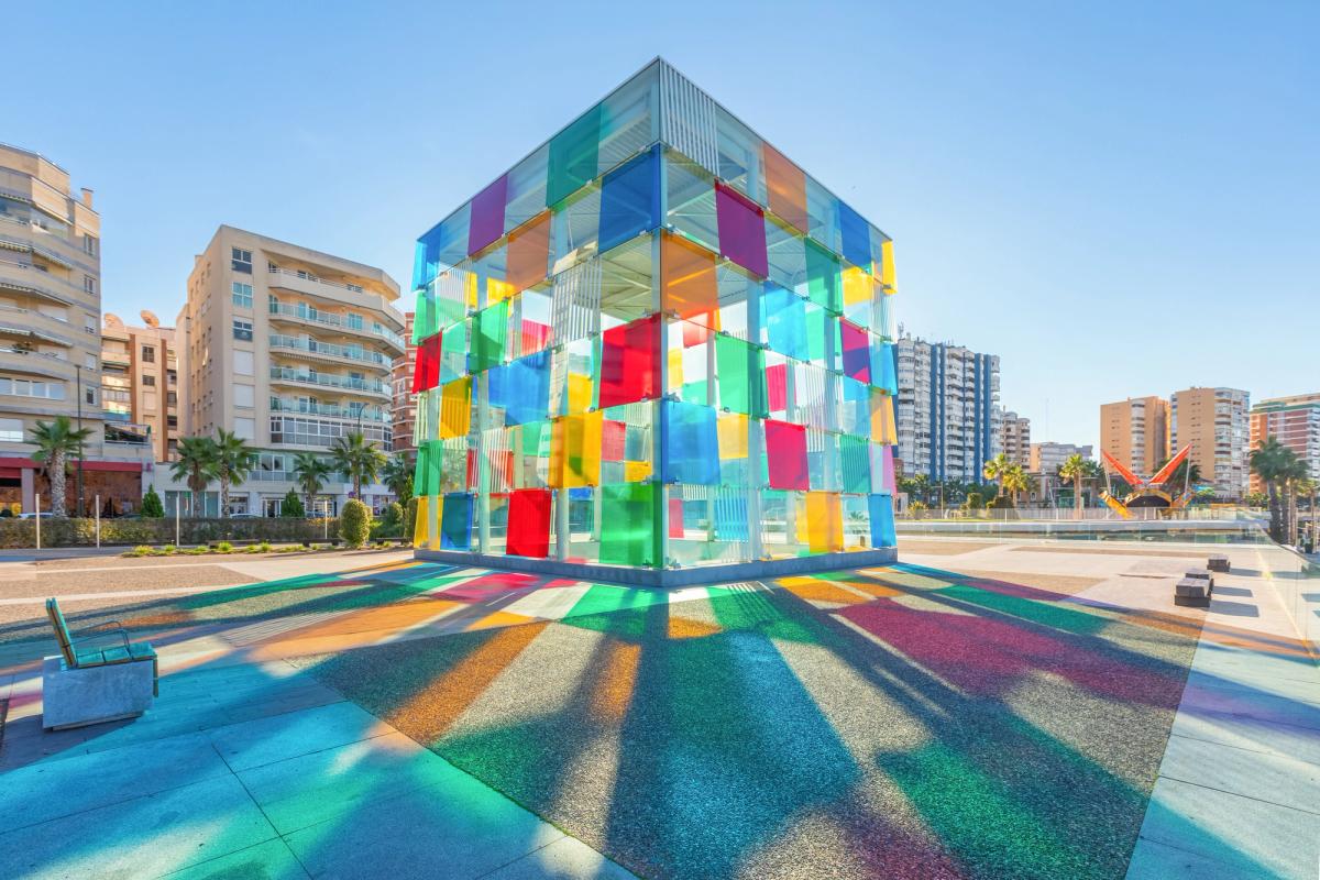 Designed by French artist Daniel Buren, a colorful glass cube houses the entrance to Centre Pompidou, located in renovated port area of Malaga, Spain. bbsferrari - stock.adobe.com.