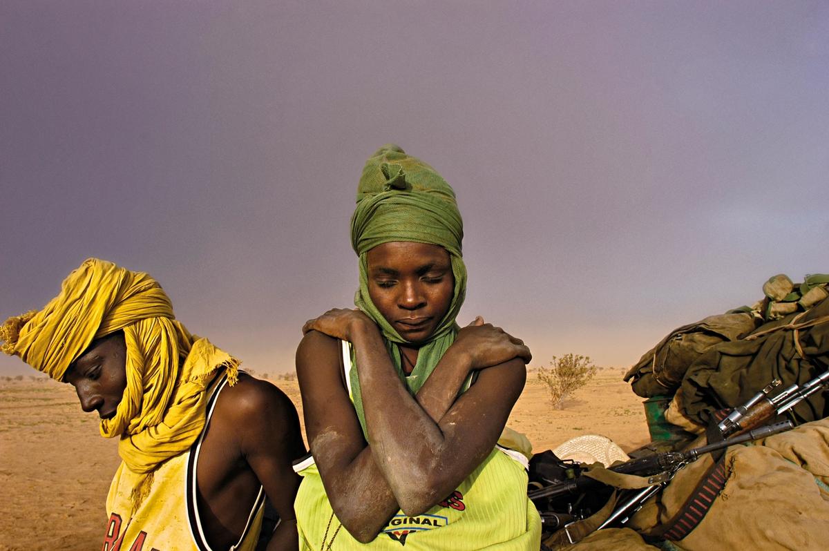 Soldiers with the Sudanese People’s Liberation Army sit by their truck, waiting for it to be repaired, as a sandstorm approaches in Darfur, Sudan, August 2004. Lynsey Addario.