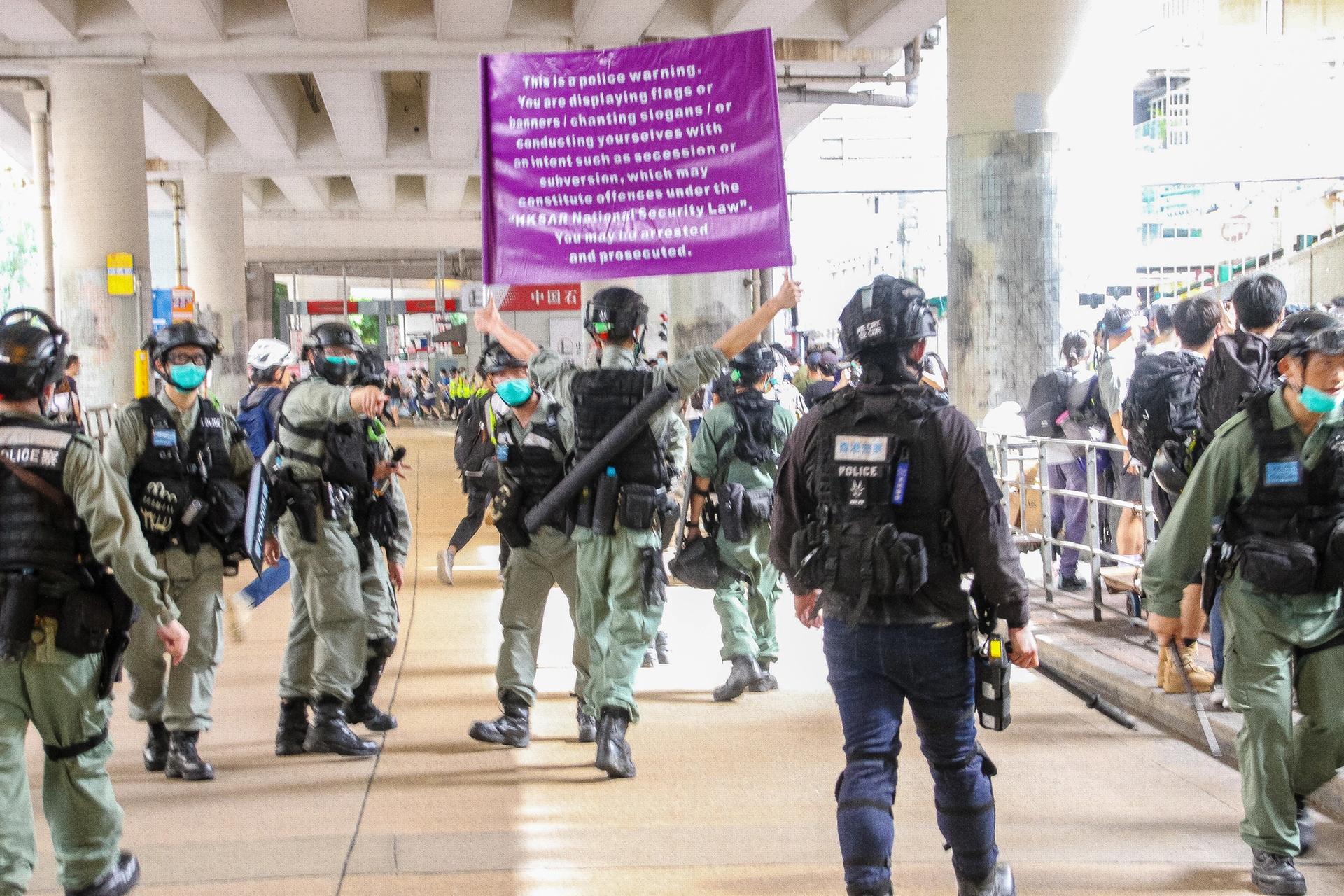 A police officer raises a purple flag that warns protesters that they are breaching the newly imported National Security Law from China during street protests in Hong Kong on 1 July Photo: Tommy Walker/NurPhoto via Getty Images