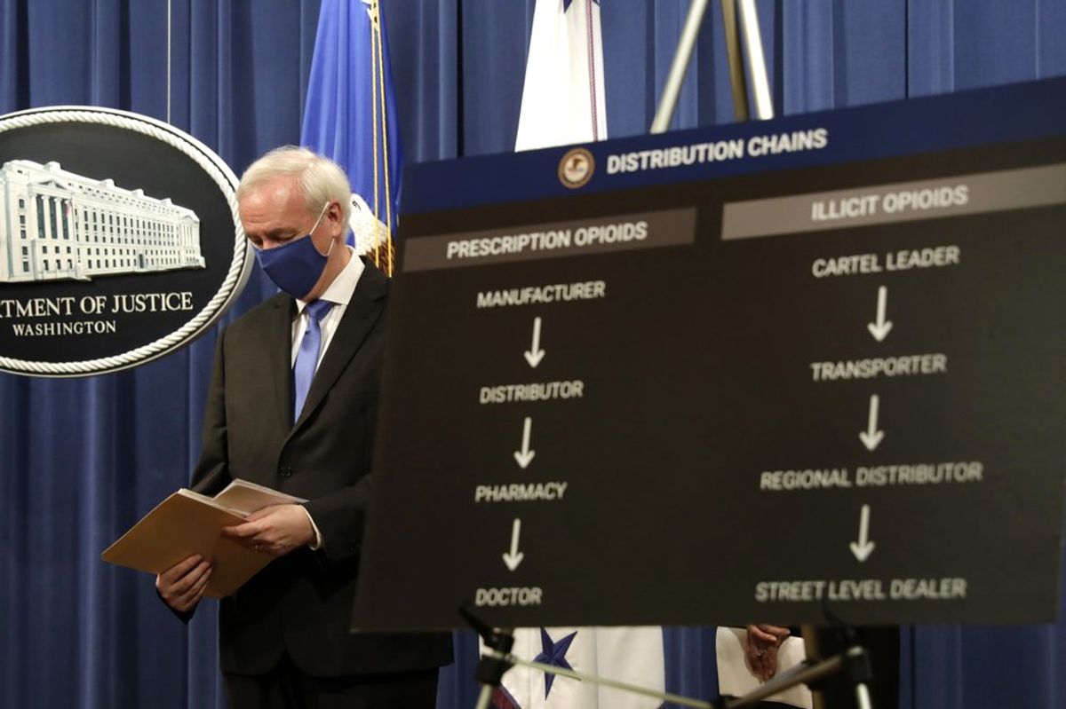 At a news conference held by Deputy Attorney General Jeffrey A. Rosen at the Justice Department in Washington, DC, a poster compares the distribution chain for prescription and illicit opioids Yuri Gripas/Pool via AP