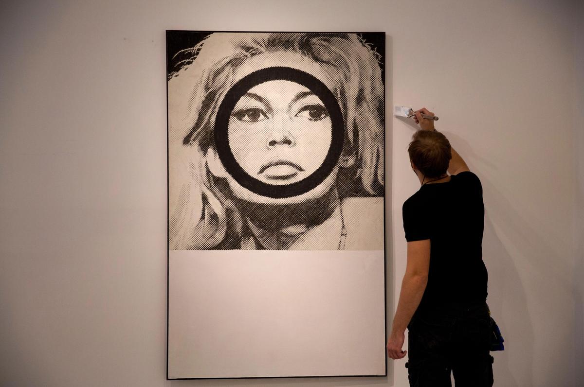 A Christie's auction house worker paints next to Gerald Laing's portrait of Brigitte Bardot
credit: Alamy