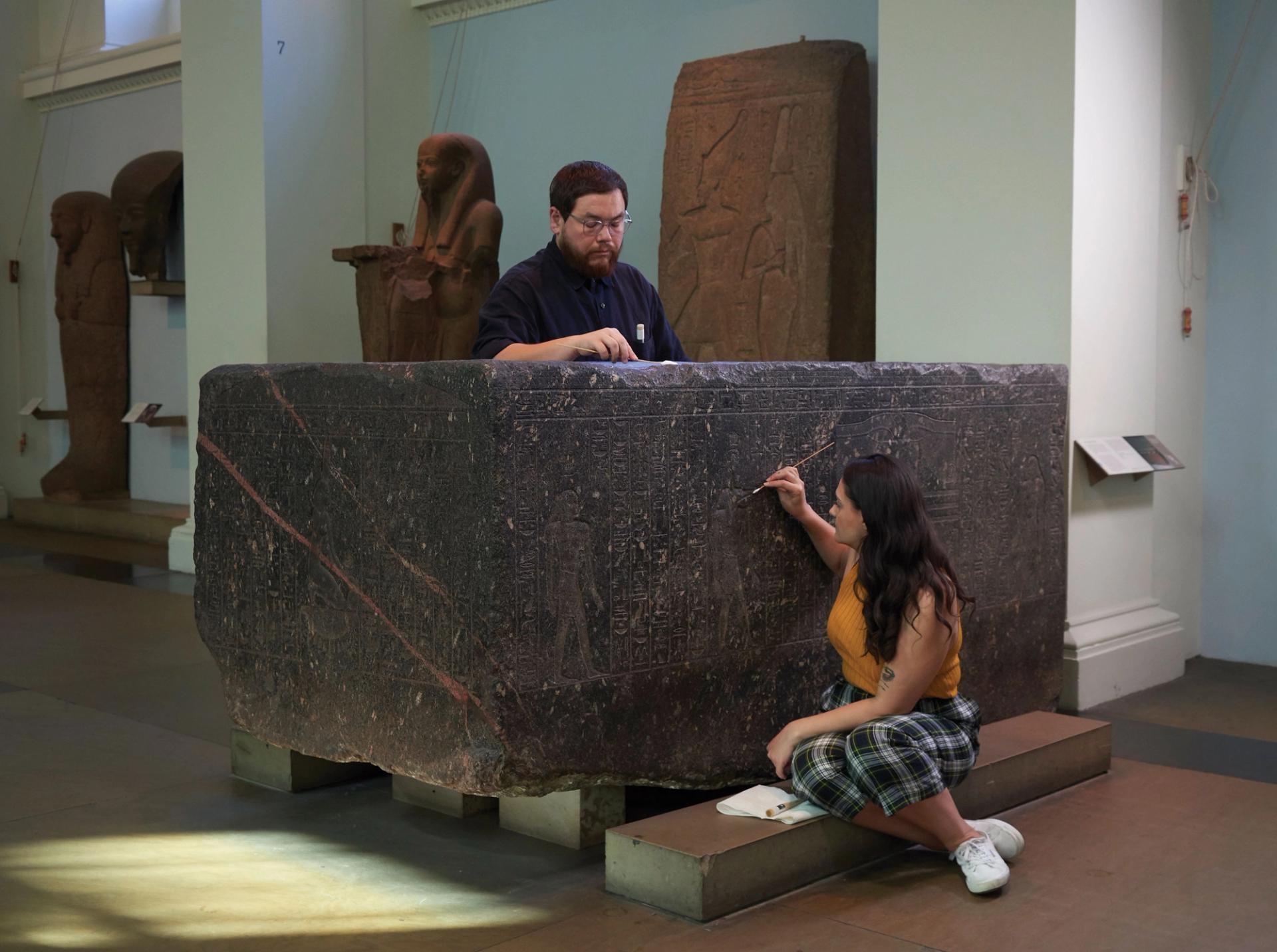 Senior conservator, Stephanie Vasiliou, and conservation student, Shoun Obana, clean The Enchanted Basin sarcophagus of Hapmen (600BC) at the British Museum, ahead of the exhibition © The Trustees of the British Museum