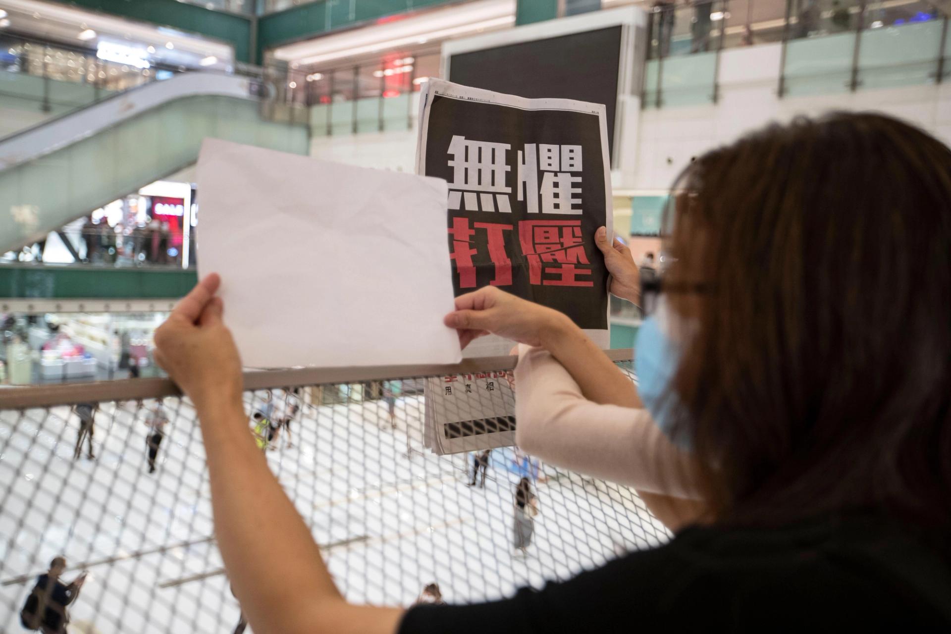 People hold up copies of the defunct Apple Daily newspaper and blank sheets as they protest for press freedom inside a mall in Hong Kong.

courtesy Alamy