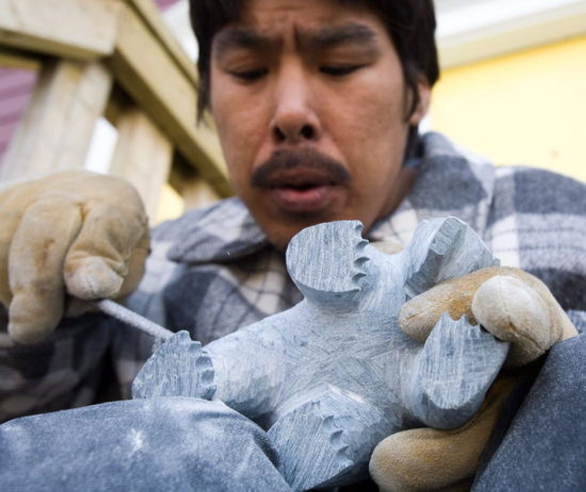 Inuit stone carver Ali Riaq of Cape Dorset works on a polar bear in Iqaluit, Nunavut. Canadian Press/Shutterstock