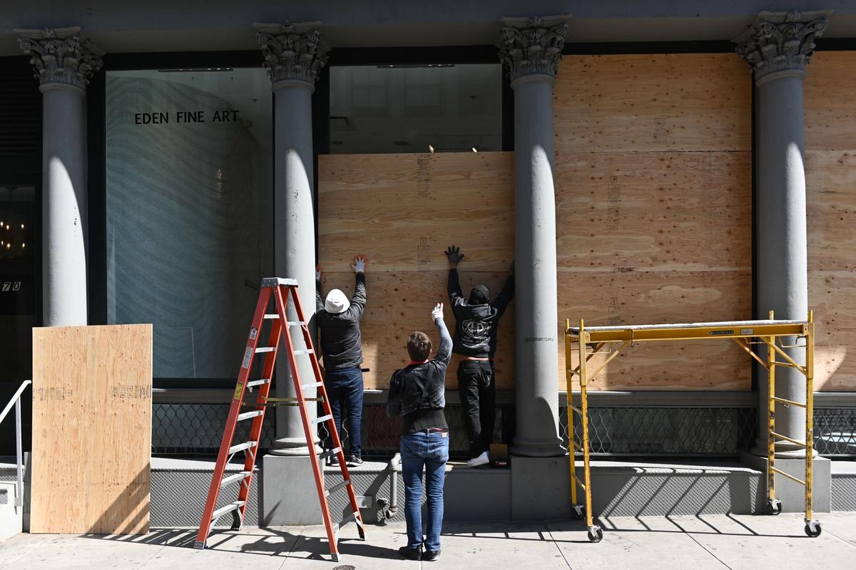 Workers board up the window of a gallery in New York in April. Erik Pendzich/Shutterstock