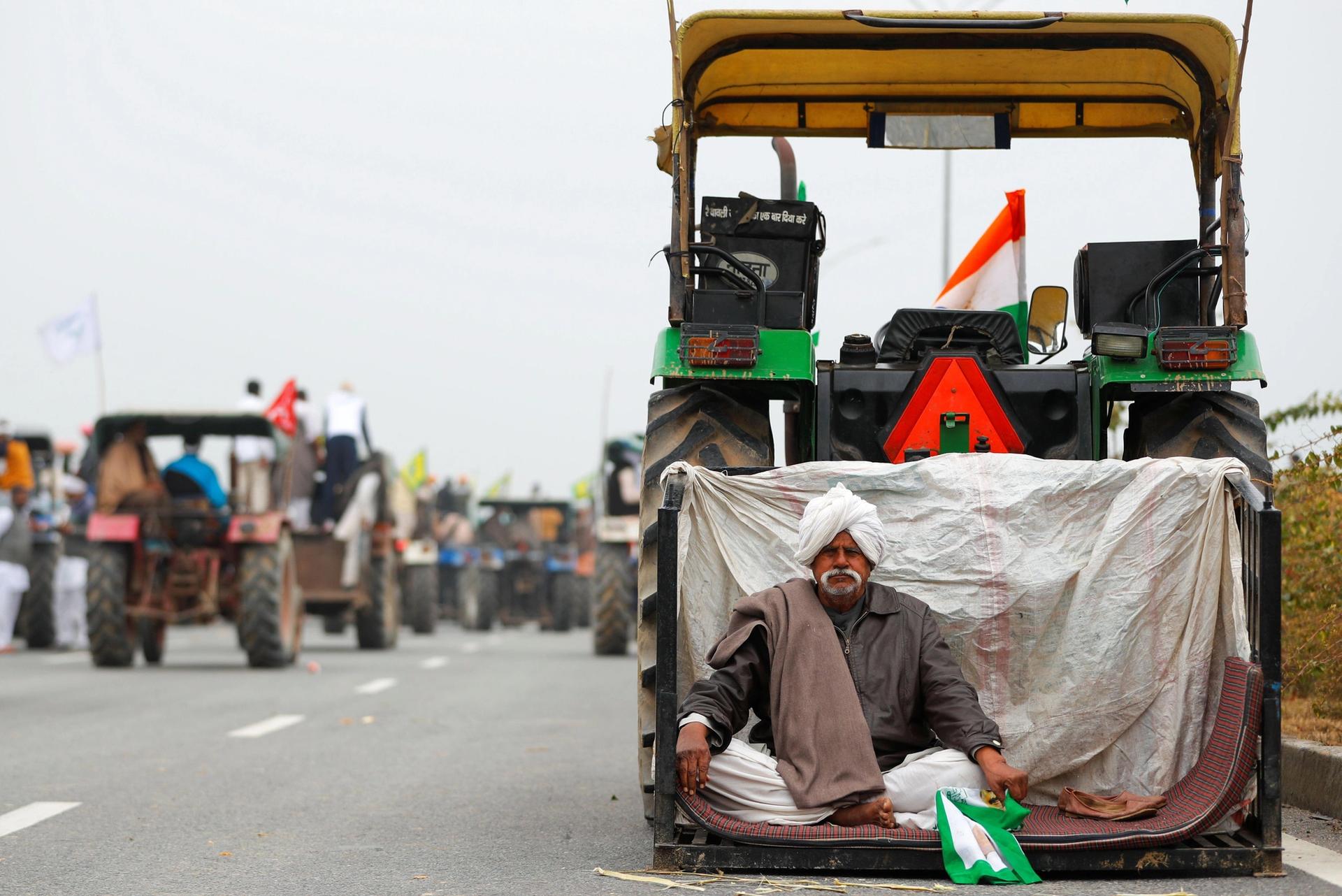 A farmer rests during a tractor rally to protest against the newly passed farm bills, on a highway on the outskirts of New Delhi, India, January 7, 2021. © REUTERS/Adnan Abidi