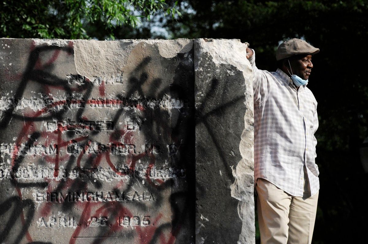 A man stands by the remains of a Confederate memorial that was removed overnight in Birmingham, Alabama. The city took down the more than 50-foot-tall obelisk following protests over the police death of George Floyd and a night of vandalism in the city Jay Reeves/AP/Shutterstock