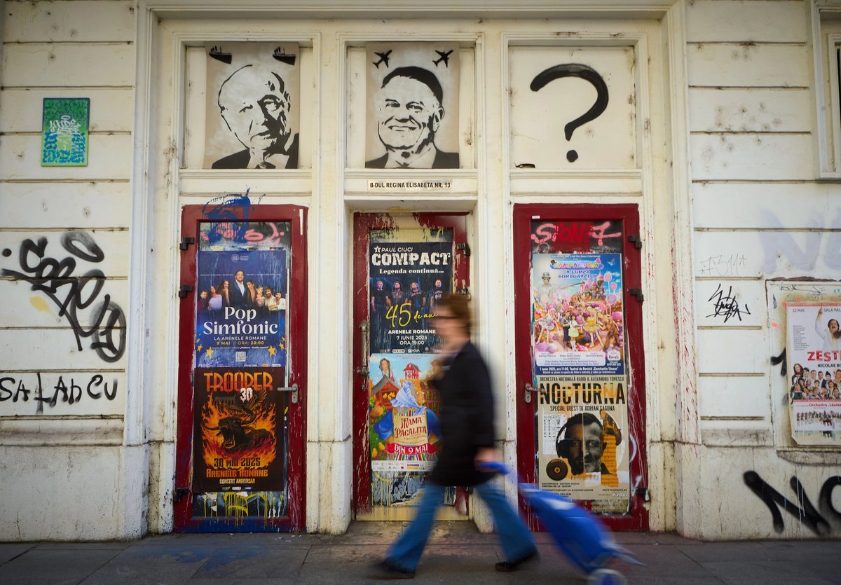 A woman walks past graffiti featuring the last two presidents of Romania, Traian Basescu and Klaus Iohannis, with a question mark in place of the third, who is set to be elected in May.
Photo: Lucian Alecu / Alamy Stock Photo
