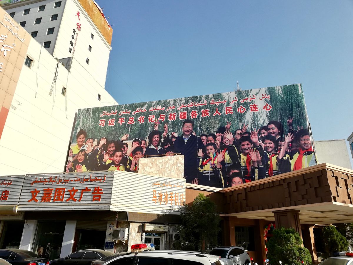 A billboard in Kashgar, a city in the Xinjiang Uyghur Autonomous Region, featuring an image of Chinese president Xi Jinping and text in Mandarin and Uyghur Photo by Kubilayaxun, via Wikimedia Commons