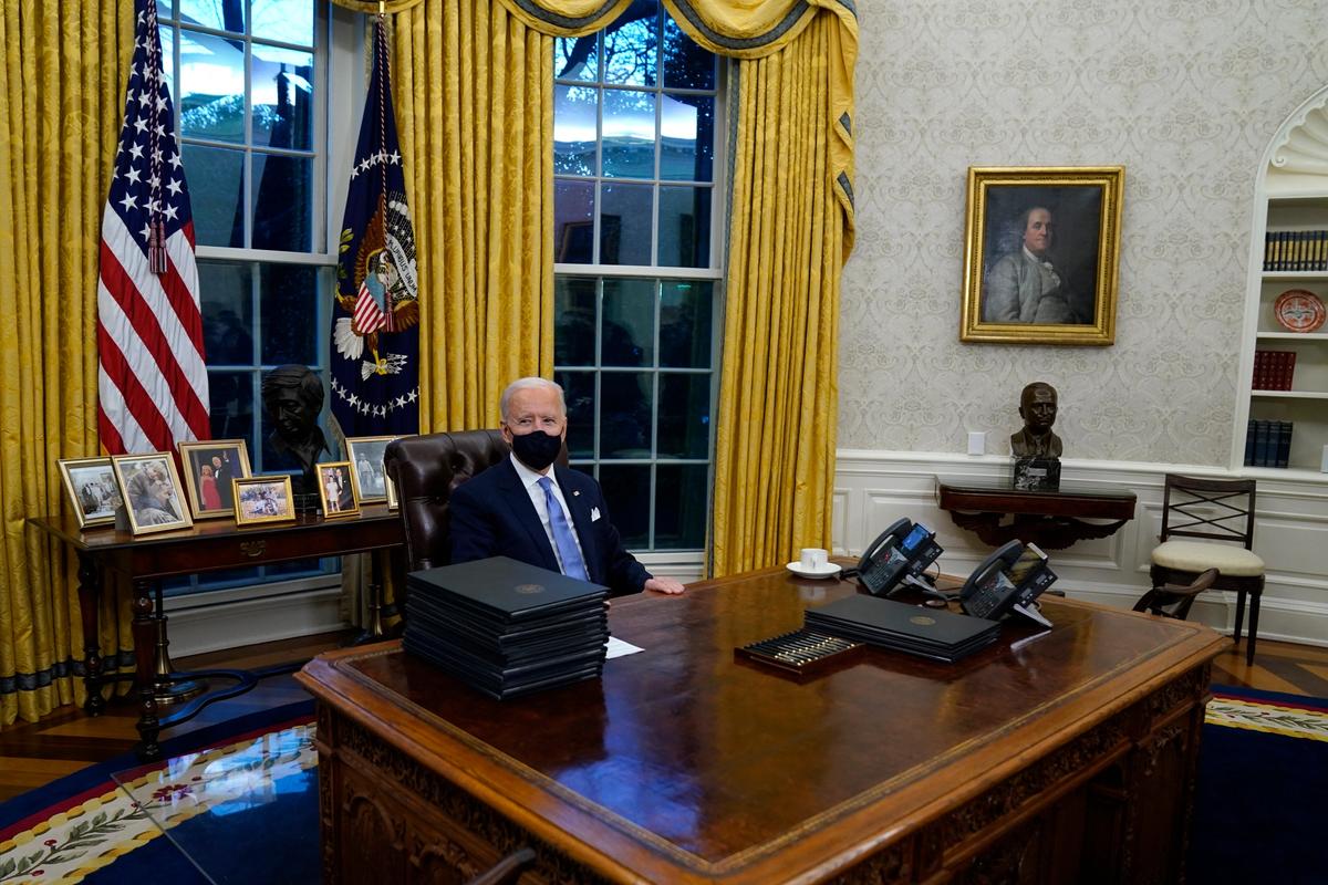 President Joe Biden signs his first executive orders in the Oval Office of the White House on Wednesday AP Photo/Evan Vucci