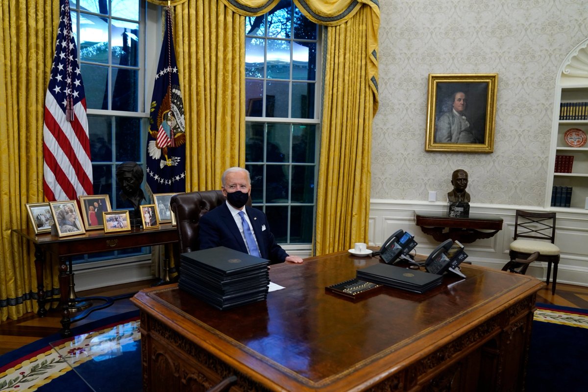 President Joe Biden signs his first executive orders in the Oval Office of the White House on Wednesday AP Photo/Evan Vucci