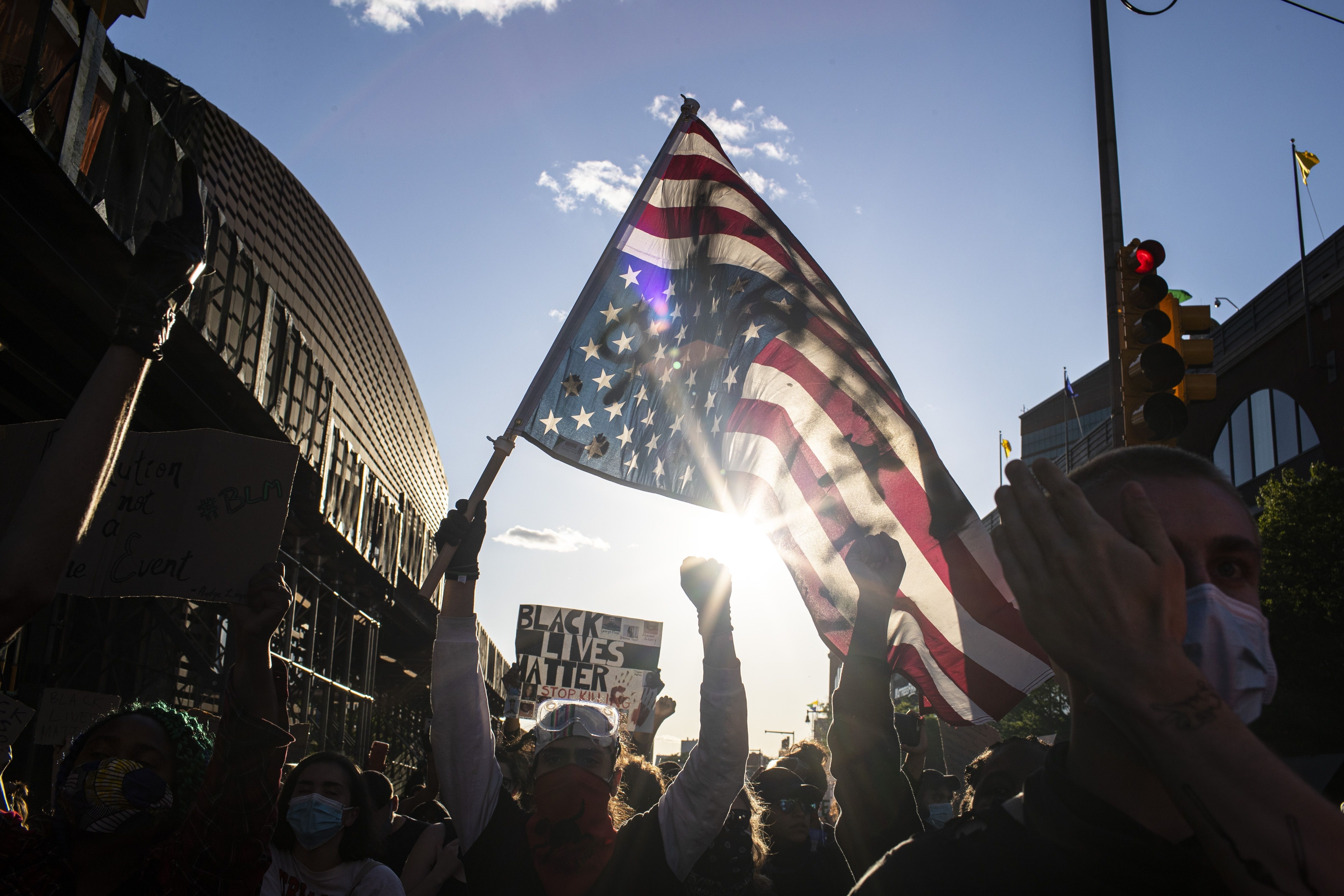 A man holds a US flag upside down, a sign of distress, as protesters march down the street during a solidarity rally for George Floyd, in Brooklyn. Protests were held throughout the country over the death of Floyd, a black man in police custody in Minneapolis who died after being restrained by police officers on 25 May. Wong Maye-E/AP/Shutterstock