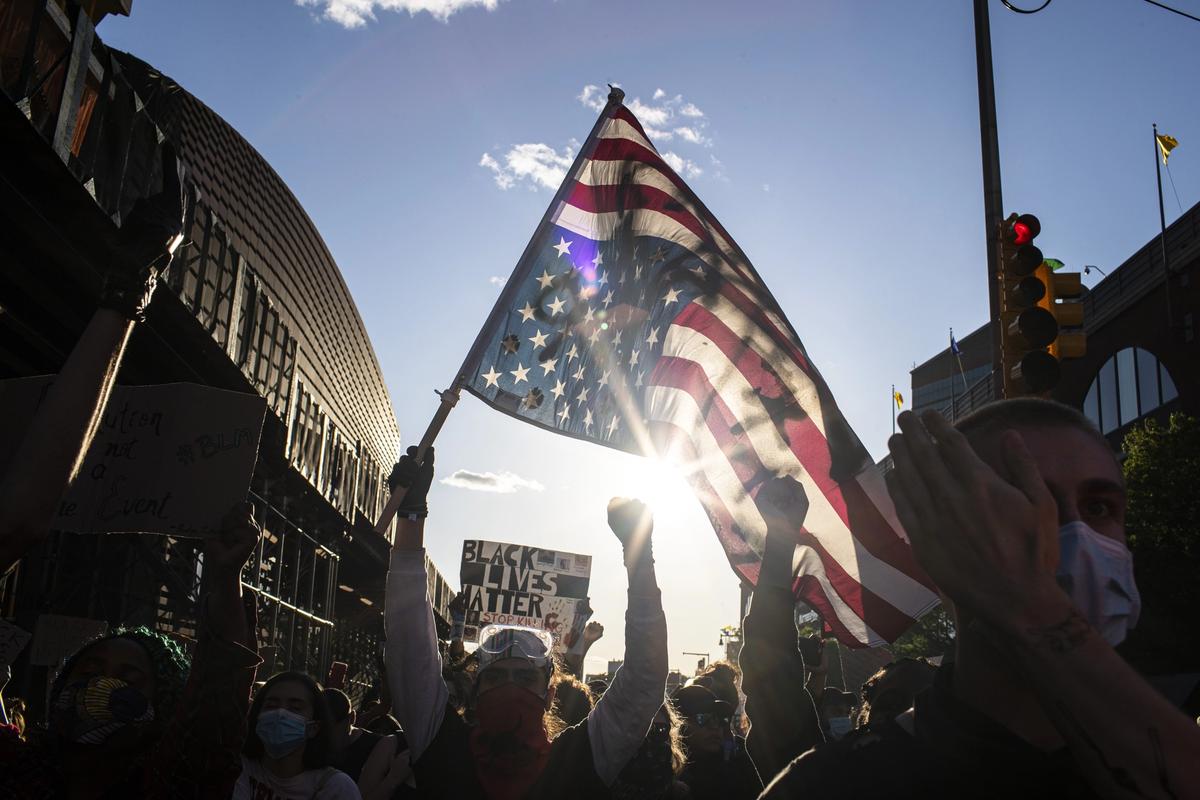 A man holds a US flag upside down, a sign of distress, as protesters march down the street during a solidarity rally for George Floyd, in Brooklyn. Protests were held throughout the country over the death of Floyd, a black man in police custody in Minneapolis who died after being restrained by police officers on 25 May. Wong Maye-E/AP/Shutterstock